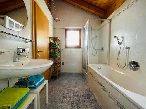 法尔泽斯奥博豪斯霍夫公寓的浴室配有水槽、淋浴和浴缸。