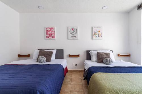 墨西哥城Condesa, Depto 2 recamaras.的一间卧室配有两张带蓝白色床单的床