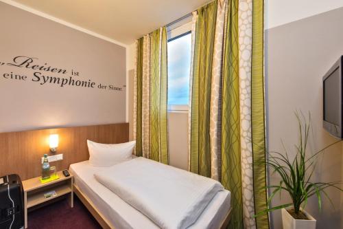 美因河畔法兰克福总站酒店的一间小卧室,配有床和窗户