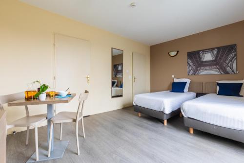 马尼·莱斯·阿莫Zenitude Hôtel-Résidences Magny-les-Hameaux的酒店客房设有两张床和一张桌子。