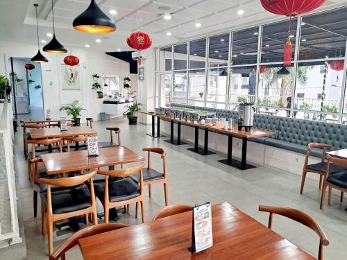 棉兰Cordela Inn Millennium Medan的餐厅设有木桌、椅子和窗户。