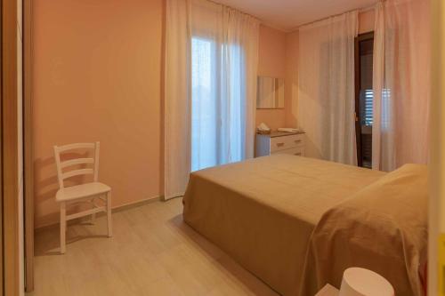 帕埃斯图姆Villa Vimani的卧室配有床、椅子和窗户。