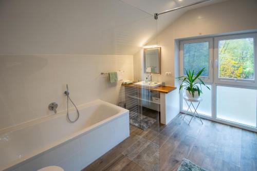 Rödental老磨坊餐厅酒店的白色的浴室设有浴缸、水槽和窗户。