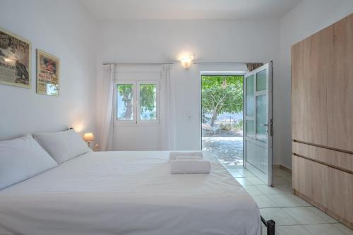 普拉基亚斯Vrisidia Cottage - Nature, Seaview & Relax的卧室配有一张白色大床和滑动玻璃门
