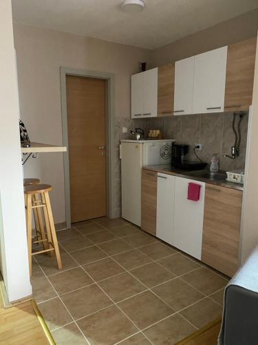 鲁马Apartman Stojadinović的厨房配有白色橱柜和瓷砖地板。