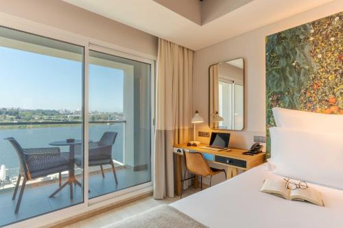 波尔图Pestana Douro Riverside的酒店客房设有一张床、一张书桌和一个阳台。
