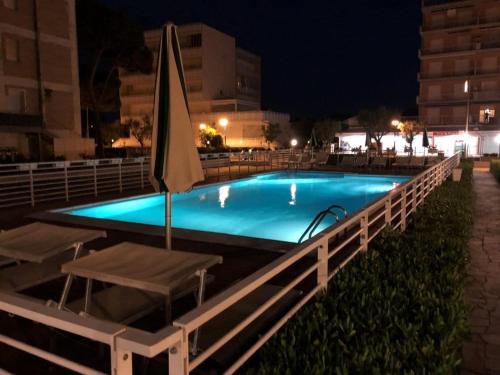 丽都迪萨维奥Hotel Lima的夜间游泳池,配有遮阳伞和椅子