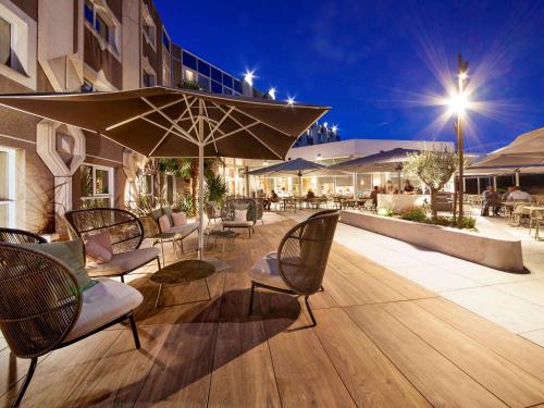 克莱蒙费朗克莱蒙费朗诺富特酒店的庭院配有椅子和遮阳伞及桌子。