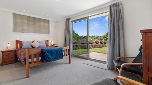 陶朗加The Lakehouse - Tauranga Holiday Home的一间卧室设有一张床和一个滑动玻璃门