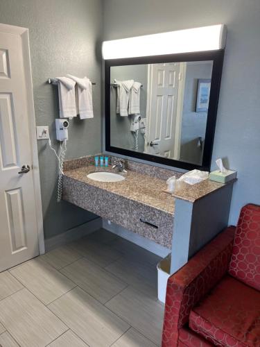 布兰登Brandon Motor Lodge的浴室设有水槽、镜子和红色椅子