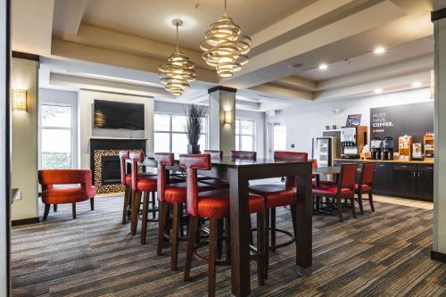 New MartinsvilleHoliday Inn Express & Suites New Martinsville, an IHG Hotel的一间带桌子和红色椅子的用餐室