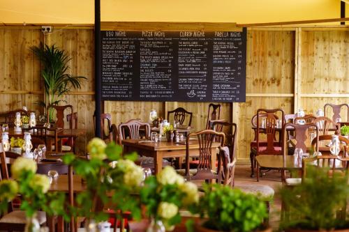 埃文河畔布拉德福伍利农庄奢华家庭旅馆的餐厅设有桌椅,墙上有菜单