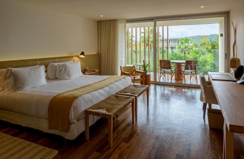安格拉杜斯雷斯Hotel Fasano Angra dos Reis的酒店客房带一张床、一张桌子和椅子