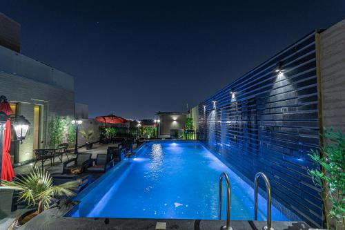 利雅德Land walk Hotel的一座建筑物边的游泳池晚上有灯光