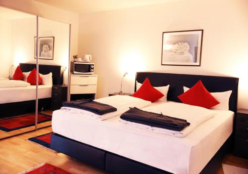 拉姆斯泰因-米森巴赫Hotel Rosenhof GmbH的一间卧室配有两张带红色枕头的床