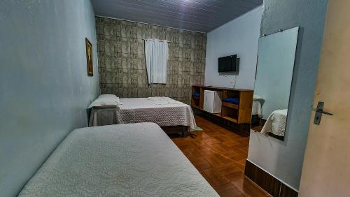 沙帕达-杜斯吉马朗伊斯Pousada Portal的小房间设有两张床和电视