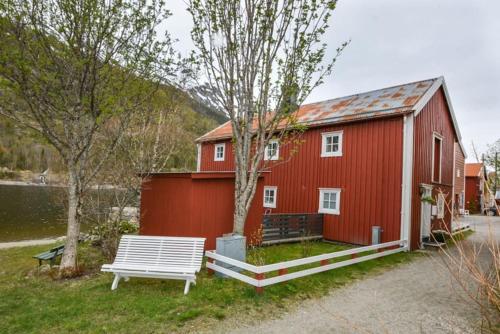 莫舍恩Sjøgata Riverside Rental and Salmon Fishing的前面有长凳的红色谷仓