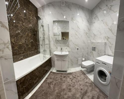 基希讷乌Apartment in center of Chisinau的浴室配有盥洗池、卫生间和洗衣机。