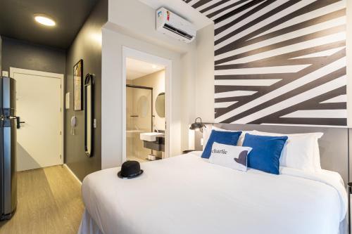 圣保罗House of Charlie Vila Mariana的卧室配有带蓝色枕头的大型白色床
