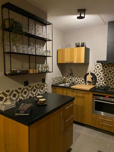 宁斯佩特Huusje18的厨房配有木制橱柜和黑色台面