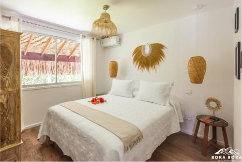 波拉波拉Villa Noa Noa - Matira的卧室配有带鲜花的白色床