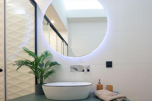 AsprouliánoiBlack Caviar的一间带白色浴缸和圆镜子的浴室