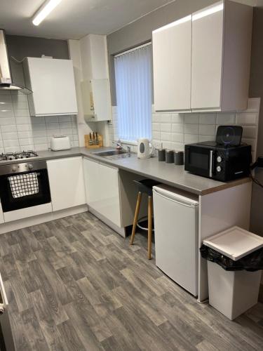 谢菲尔德Sheffield spa view 2 bed house free parking的厨房配有白色橱柜和黑微波炉