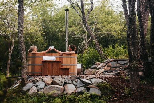 Meaghers GrantFlowEdge Riverside Getaway的两名妇女站在树林里的热水浴缸中