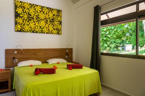 波拉波拉FARE ATEA的一间卧室配有绿色的床和红色枕头