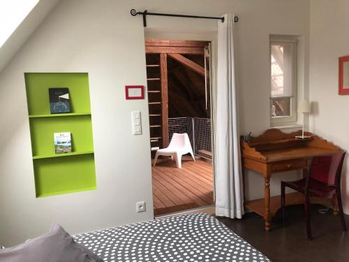 BourgheimB&B Le Lodge的一间卧室配有书桌,一扇门通往一个房间