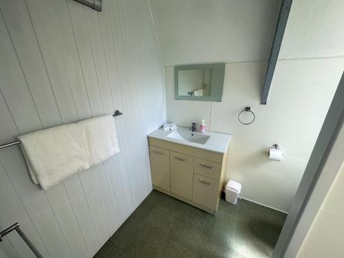 科罗曼德镇Pohutukawa Coastal Chalets的白色的浴室设有水槽和镜子