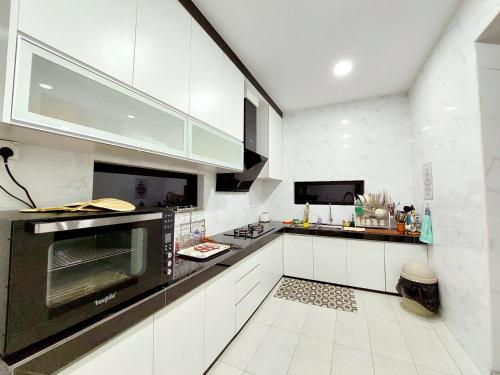 马六甲Good2Stay Villa的厨房配有白色橱柜和黑烤箱。