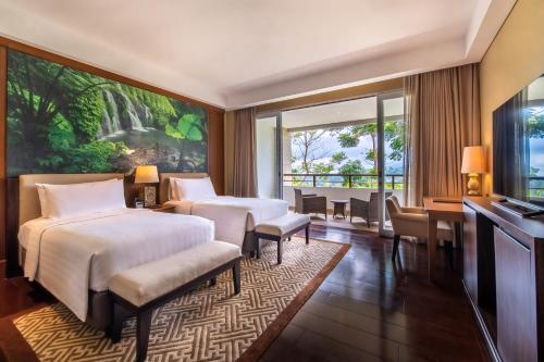 贝都古HOMM Saranam Baturiti, Bali的一间卧室设有两张床、一张桌子和一个窗口。