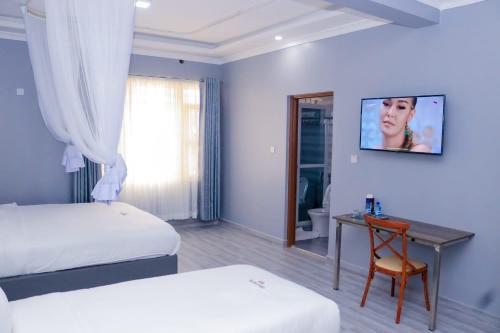 基苏木The VIP Luxury Lounge Hotel的一间卧室设有两张床和一张桌子,墙上配有电视