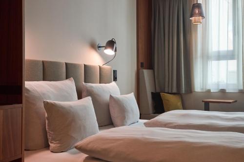 慕尼黑科库恩塞德林格托酒店的酒店的客房 - 带2张带白色枕头的床