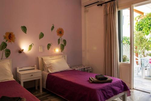 帕罗奇亚玛丽莎酒店的一间卧室设有两张带紫色床单的床和窗户。