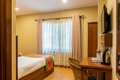 加德满都Kuna Resort的配有一张床、一张书桌和一扇窗户的酒店客房