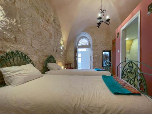 伯利恒Dar al Majus的一间卧室设有两张床和石墙