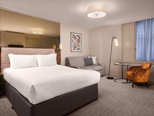 伦敦斯特兰德宫酒店的酒店客房带一张大床和一把椅子