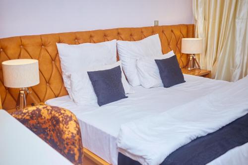 拉各斯Haven Heights Apartments的一张配有白色床单和蓝色枕头的大床