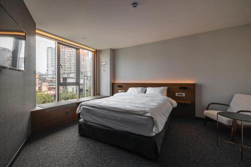 首尔Pillowsopher Hongdae的卧室配有床、椅子和窗户。