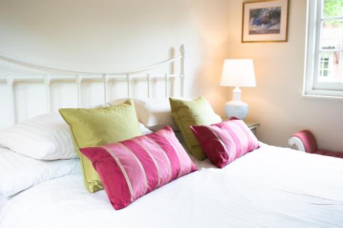 曼海德The Pack Horse Exmoor National Park Allerford Riverside Cottage & Apartments的白色的床和粉红色及绿色枕头