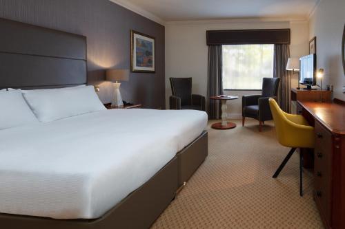 格兰瑟姆Belton Woods Hotel, Spa & Golf Resort的酒店客房设有一张大床和一张书桌。