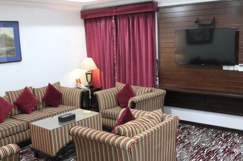 利雅德Carawan Al Khaleej Hotel Olaya的一间配备有沙发及平面电视的酒店客房