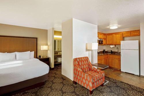 拉斯维加斯拉斯维加斯红石/萨默拉昆塔套房酒店的一间卧室配有一张床和一把椅子,一间厨房
