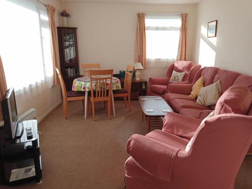 昂肯Glen Dhoo Country Cottages - Meadowview Bungalow的客厅配有红色的沙发和桌子
