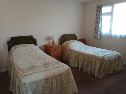 昂肯Glen Dhoo Country Cottages - Meadowview Bungalow的一间卧室设有两张床、一个梳妆台和窗户。