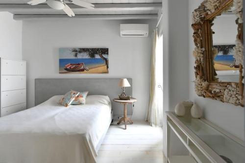 帕罗斯岛SUNRAY Paros Beach front 2 bedroom house next to kite sports的白色卧室配有床和镜子
