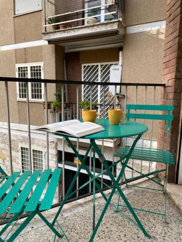 罗马卡萨马斯公寓的阳台配有一张绿色桌子和两把椅子