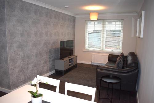福尔柯克Kelpies Serviced Apartments- Cromwell Apt的客厅配有真皮沙发和电视